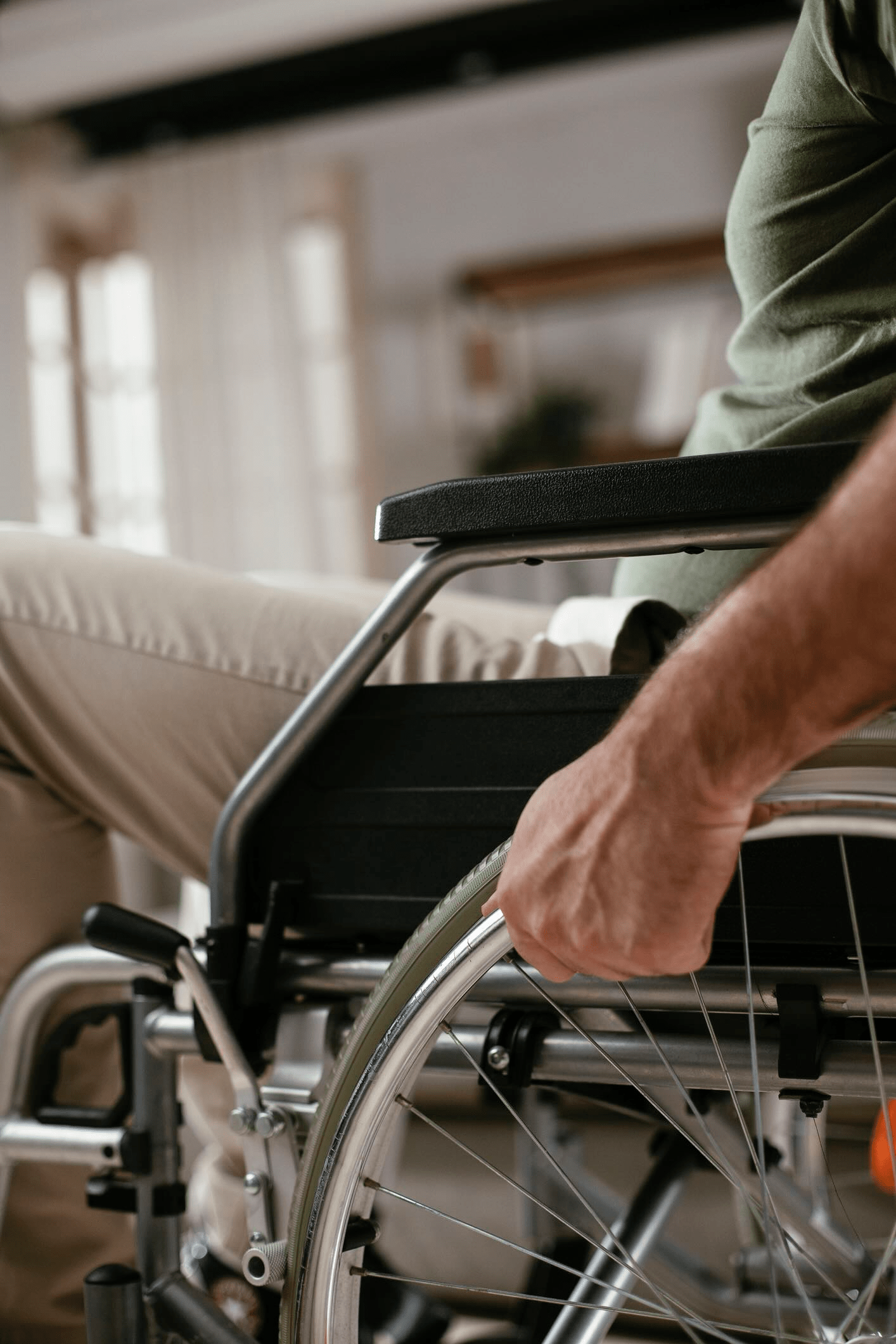 Close up of man holding wheel of wheelchair. Young disabled man in a wheelchair.