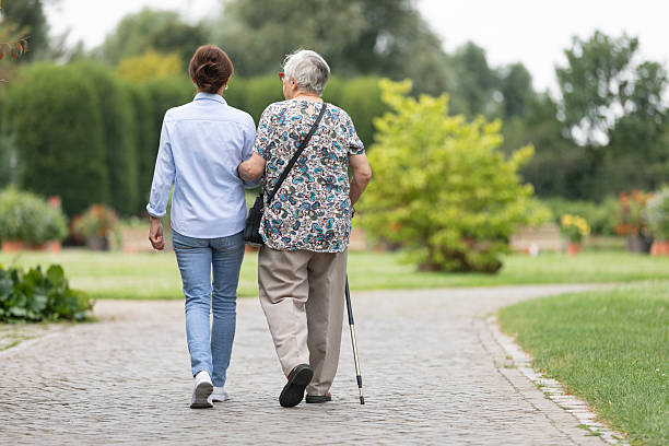 Happy senior woman and caregiver walking outdoors