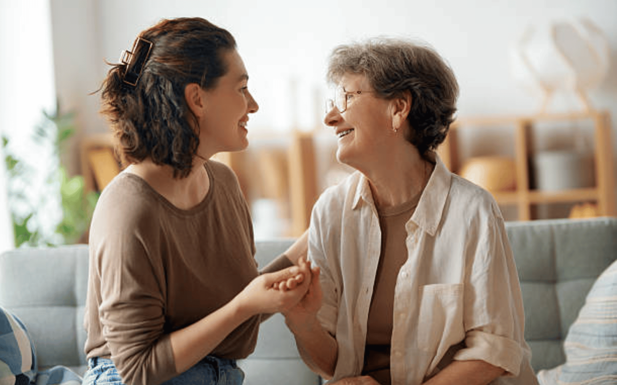 Heartwarming scene of a compassionate young woman helping her elderly mother walk with a mobility aid inside a cozy, sunlit home. The supportive relationship showcases love, trust, and intergenerational family bonds, making this image ideal for concepts like home care, aging in place, healthcare support, and family values.