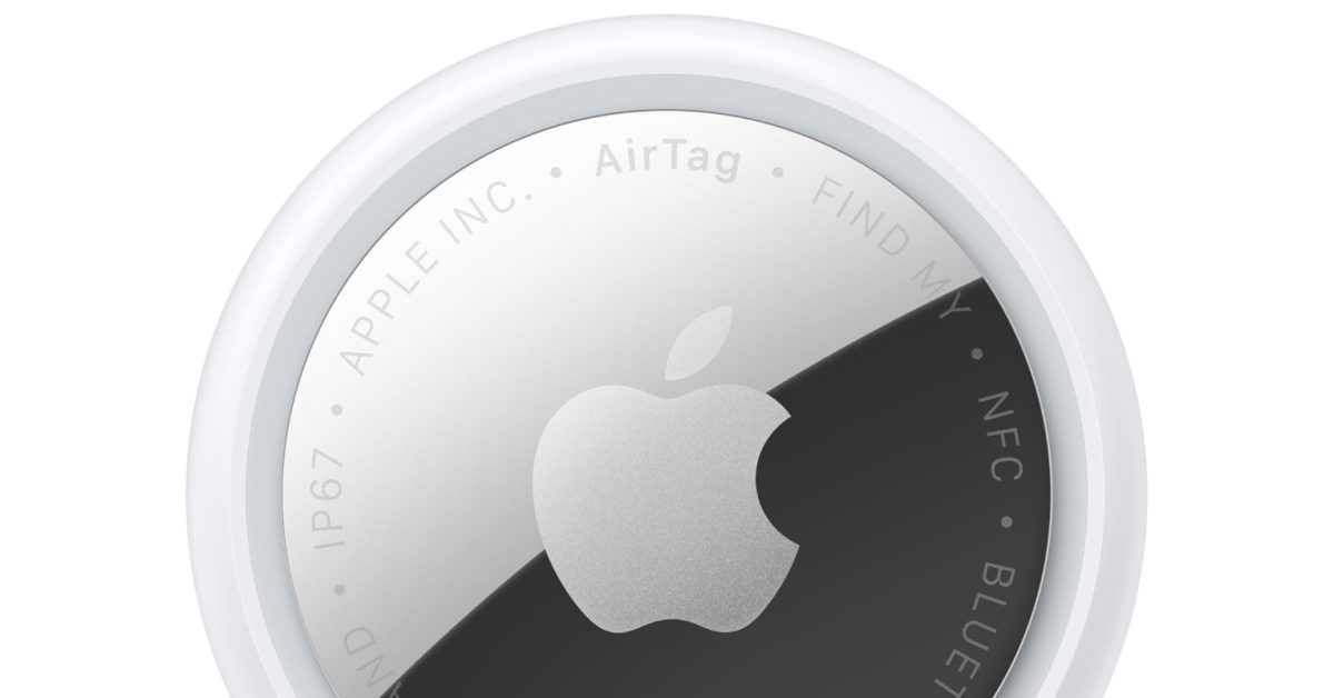 A close-up of a circular Apple AirTag tracker showing the silver Apple logo and engraved text.