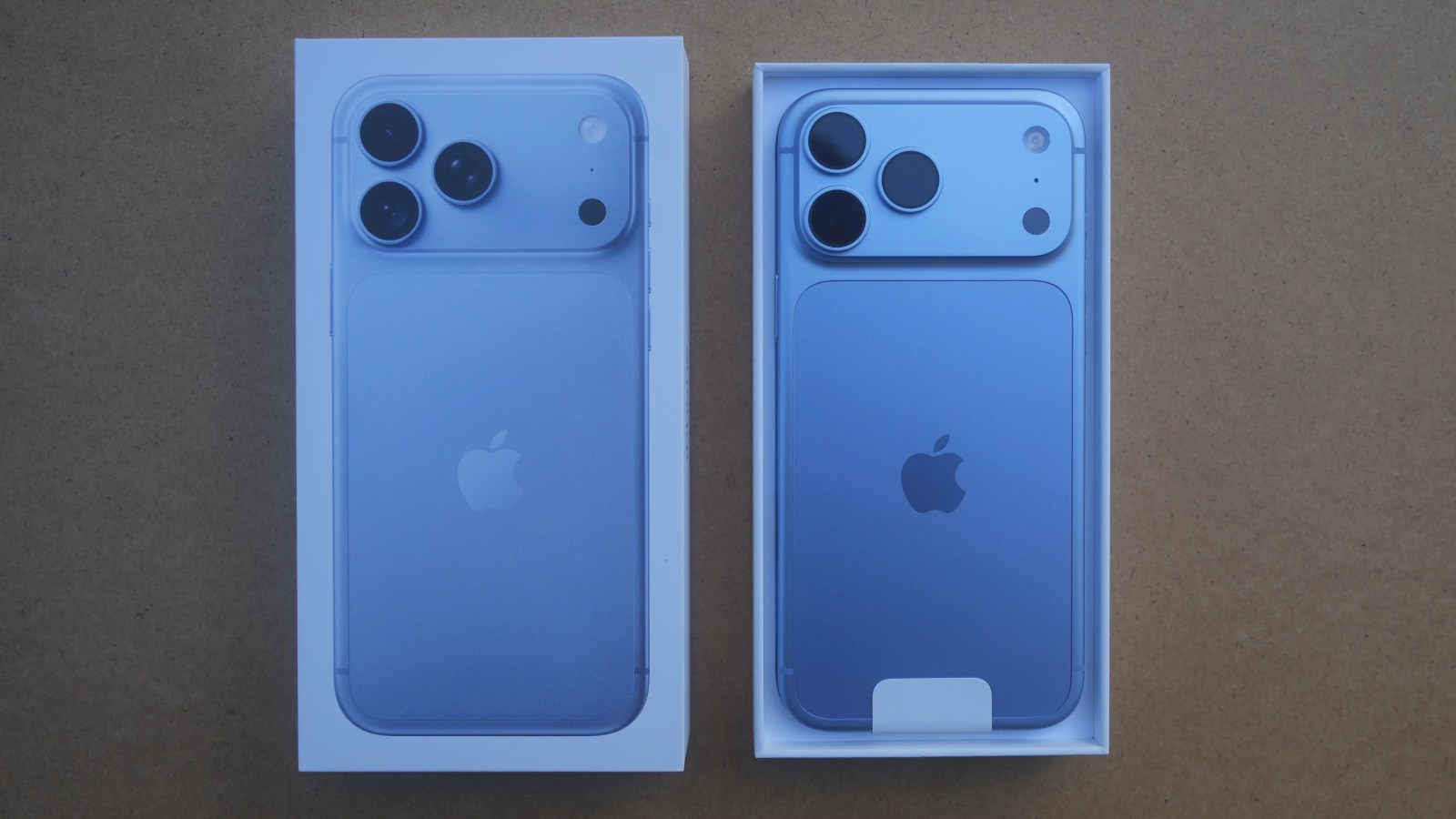 Unboxed blue smartphone displayed in packaging with a visible Apple logo and three camera lenses on the back.