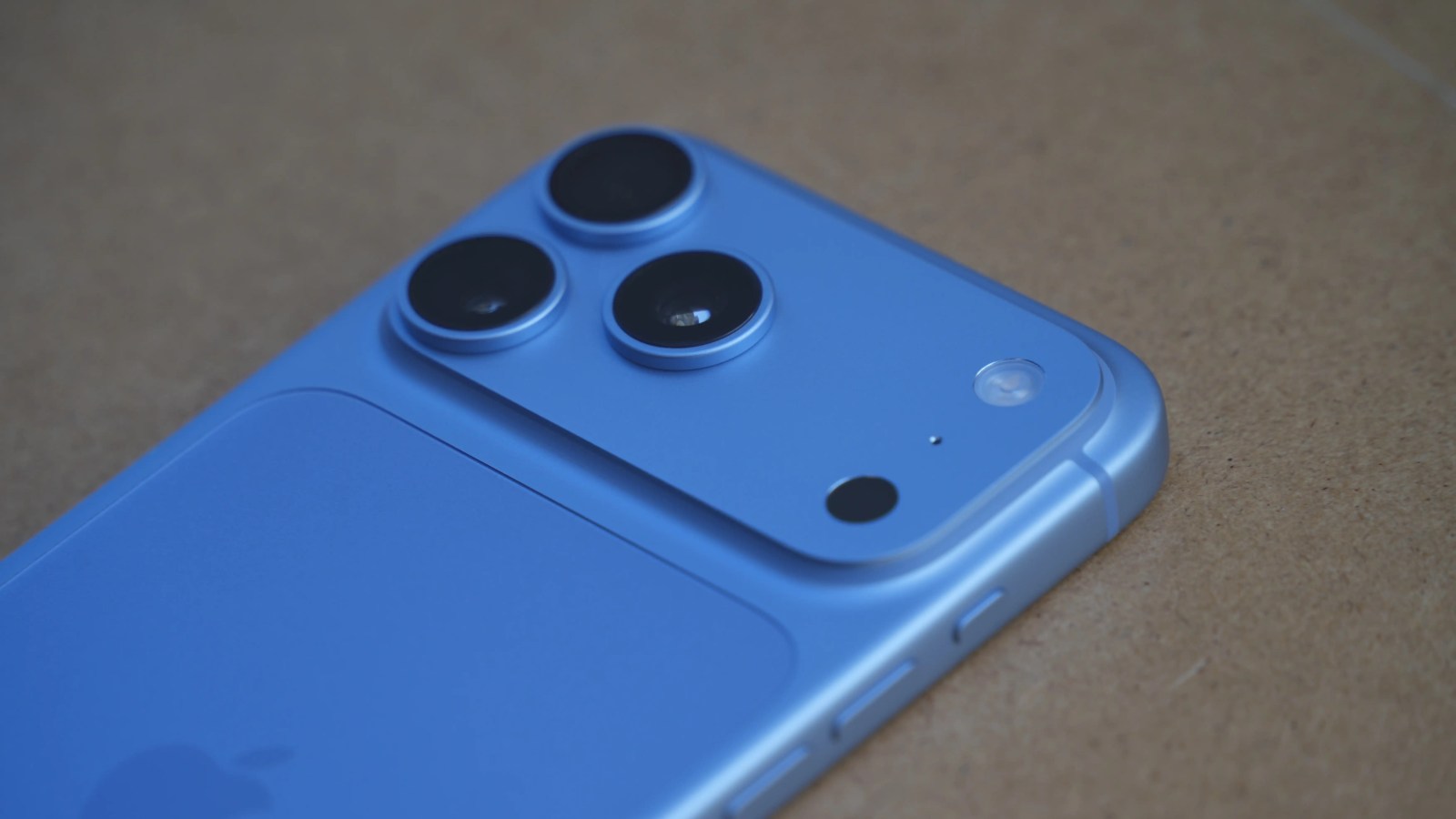 Close-up view of a blue smartphone with three camera lenses on the back.