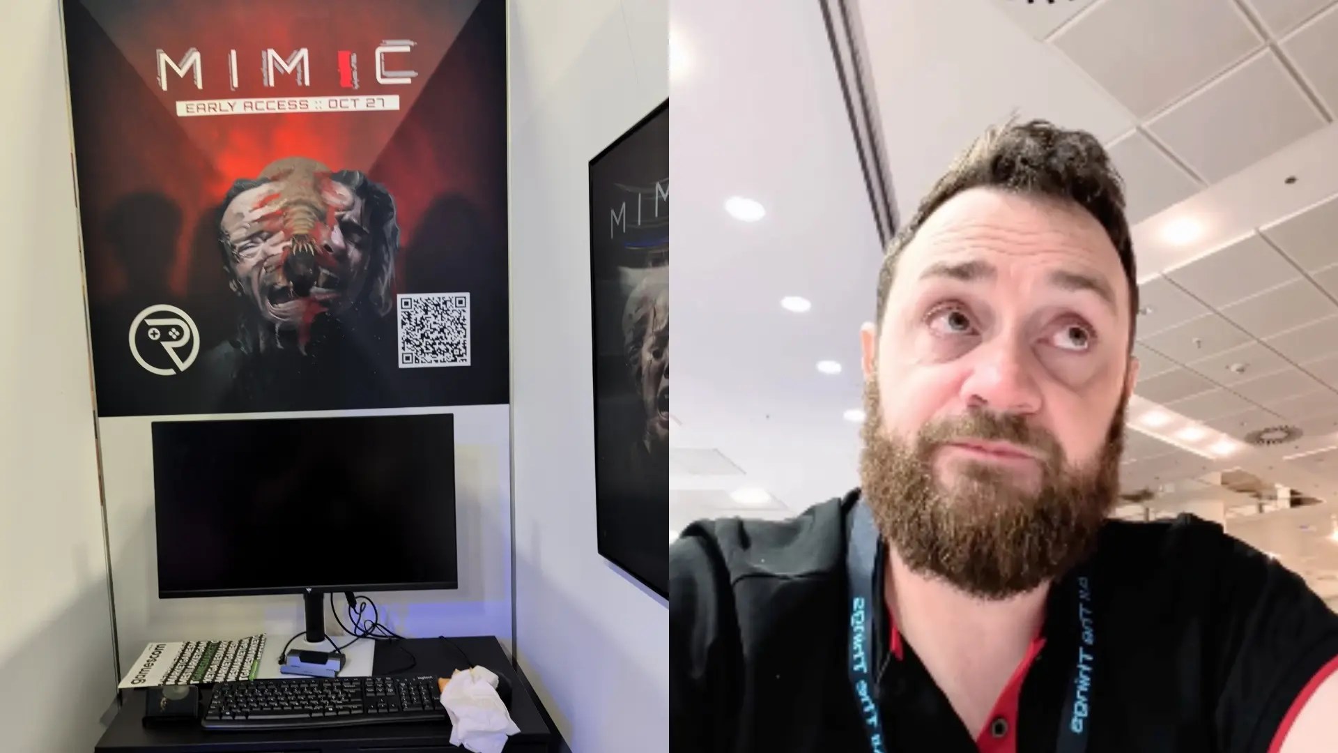 A bearded man stands next to a game booth display featuring a poster for the game Mimic.