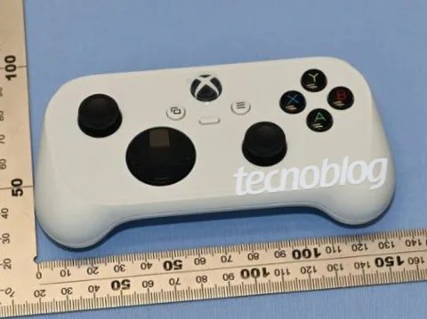 A white Xbox controller prototype rests on a blue surface next to an L-shaped measuring ruler.