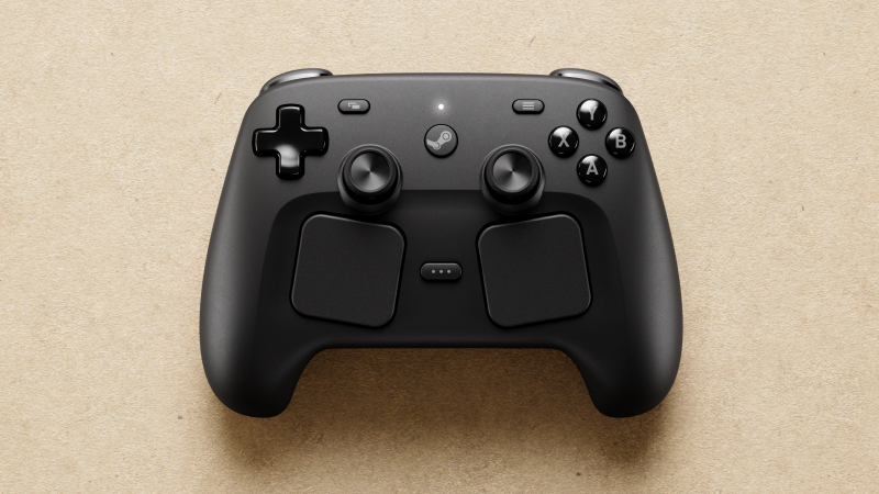 A matte black Steam game controller with dual trackpads and joysticks rests on a tan textured surface.