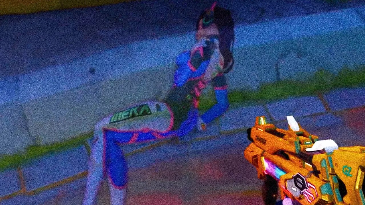 D.Va character from Overwatch reclining on a surface with a colorful background.