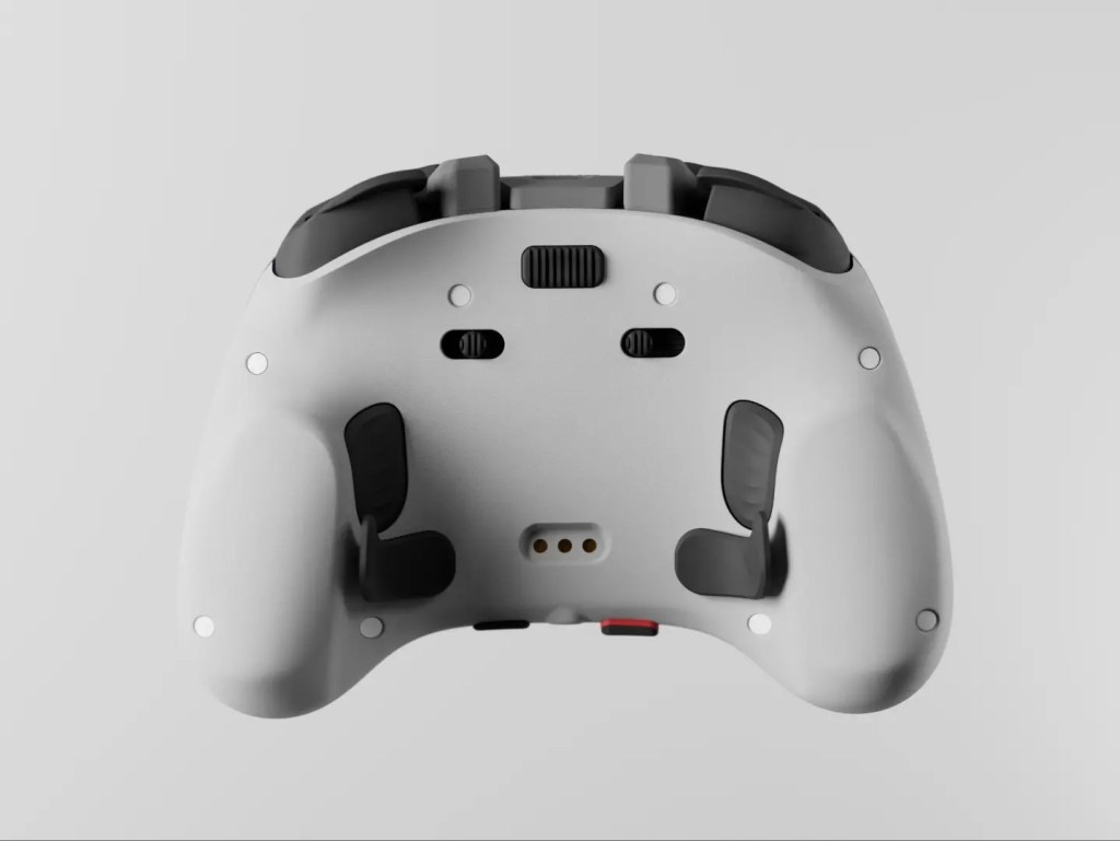 The back of a white game controller features black paddles, switches, and triggers against a light gray background.