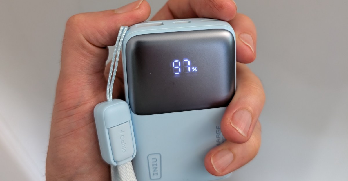 Hand holding a light blue INIU portable charger displaying a battery percentage of 97%.
