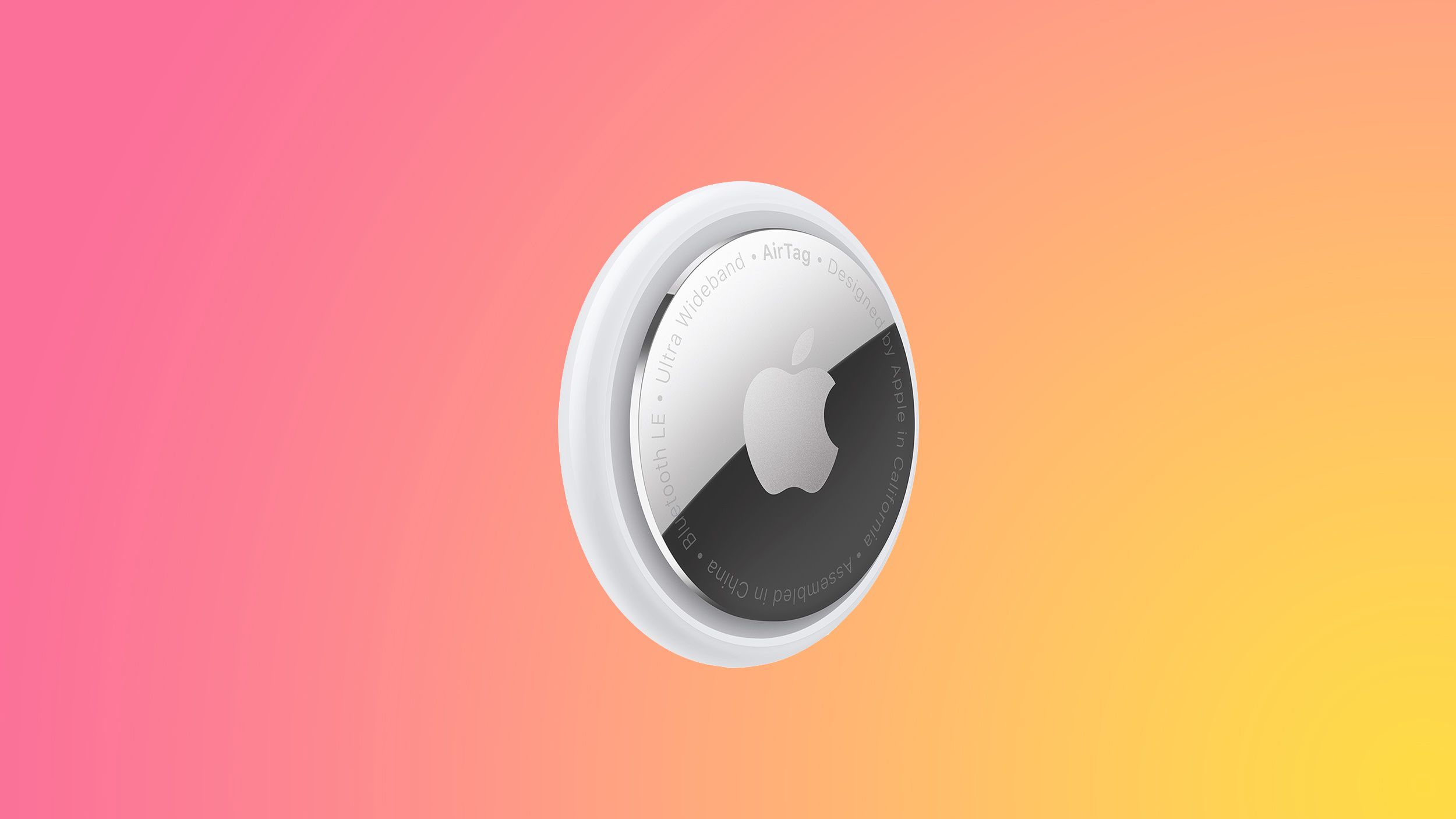 An Apple AirTag floats at an angle against a vibrant pink, orange, and yellow gradient background.