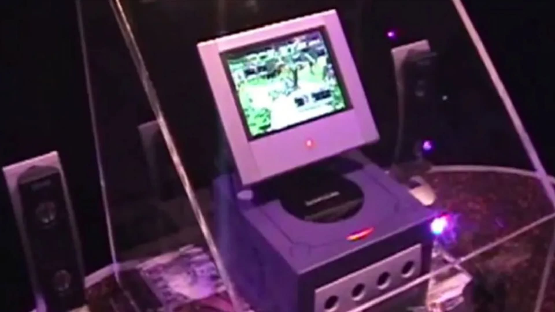 A purple Nintendo GameCube console with a screen accessory attached, set up in a display.