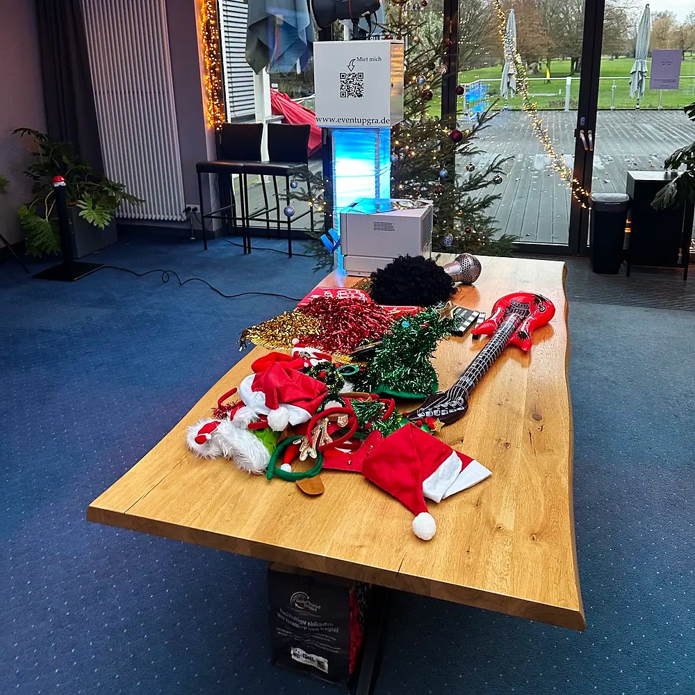 Requisiten-Tisch für die Weihnachtsfeier mit Weihnachtsmützen, Lametta und weiteren Requisiten vor der Fotobox