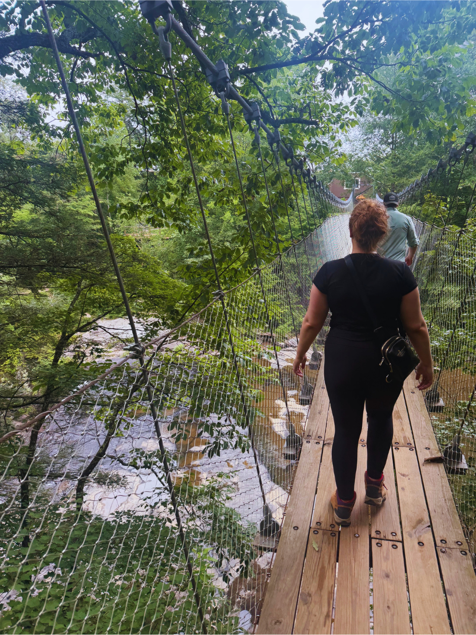 Kait walking across suspension bridge that is on the Fall Creek Falls State Park hike