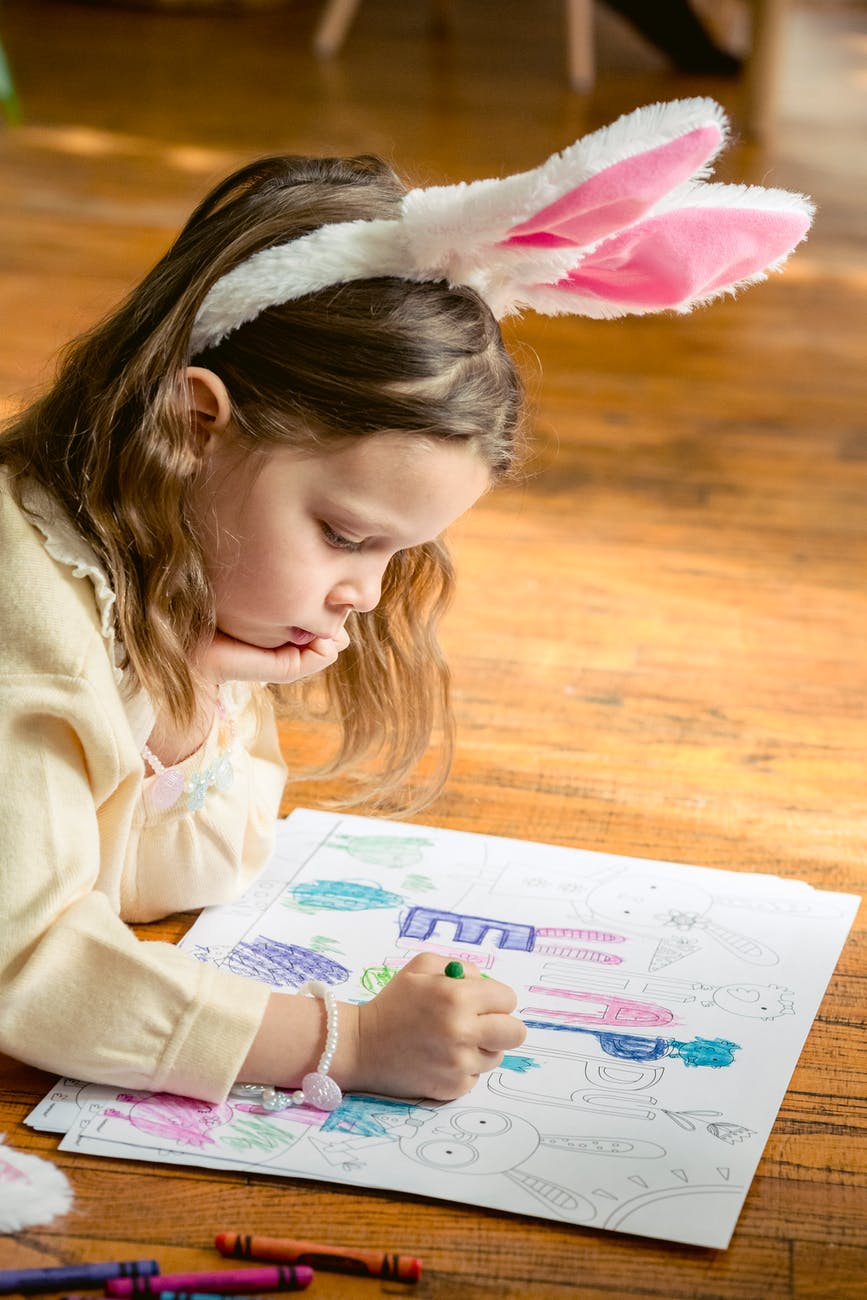 charming girl with bunny ears coloring drawing on parquet