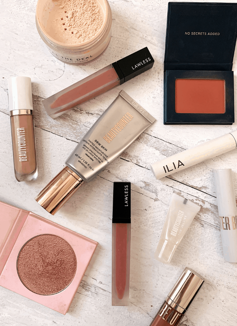 A variety of makeup products arranged on a white wooden background.