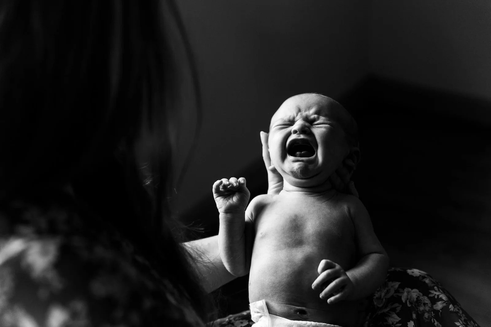 grayscale photo of person holding a new born baby