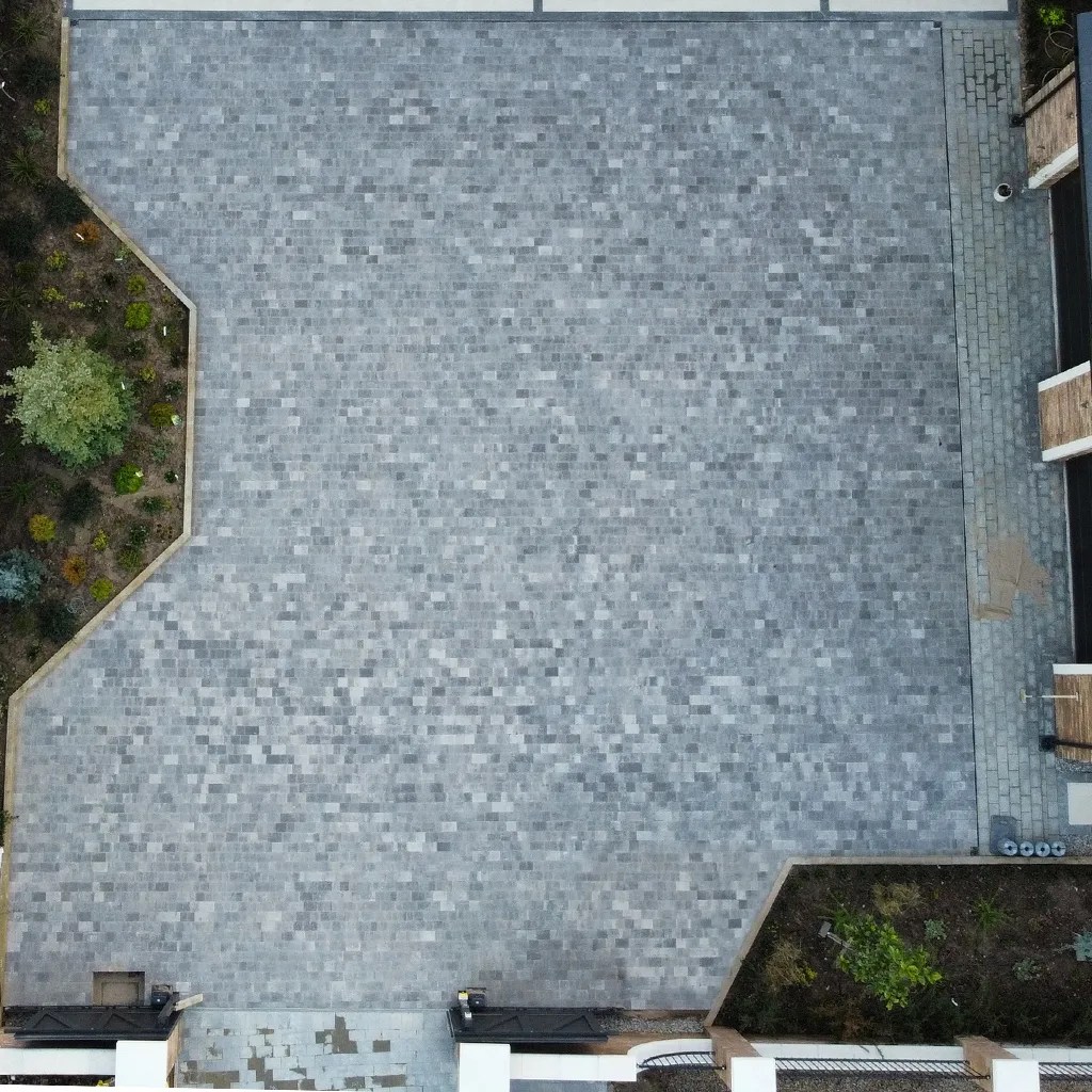 large block paved driveway with a planter on the left and bottom right.