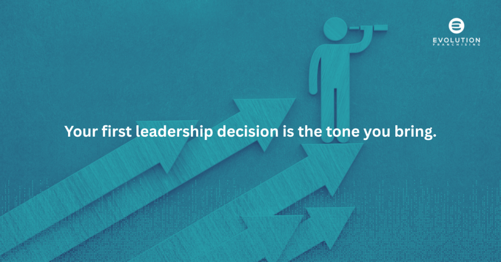 An illustration depicting a figure looking through binoculars, positioned next to upward-pointing arrows, with the text 'Your first leadership decision is the tone you bring.'