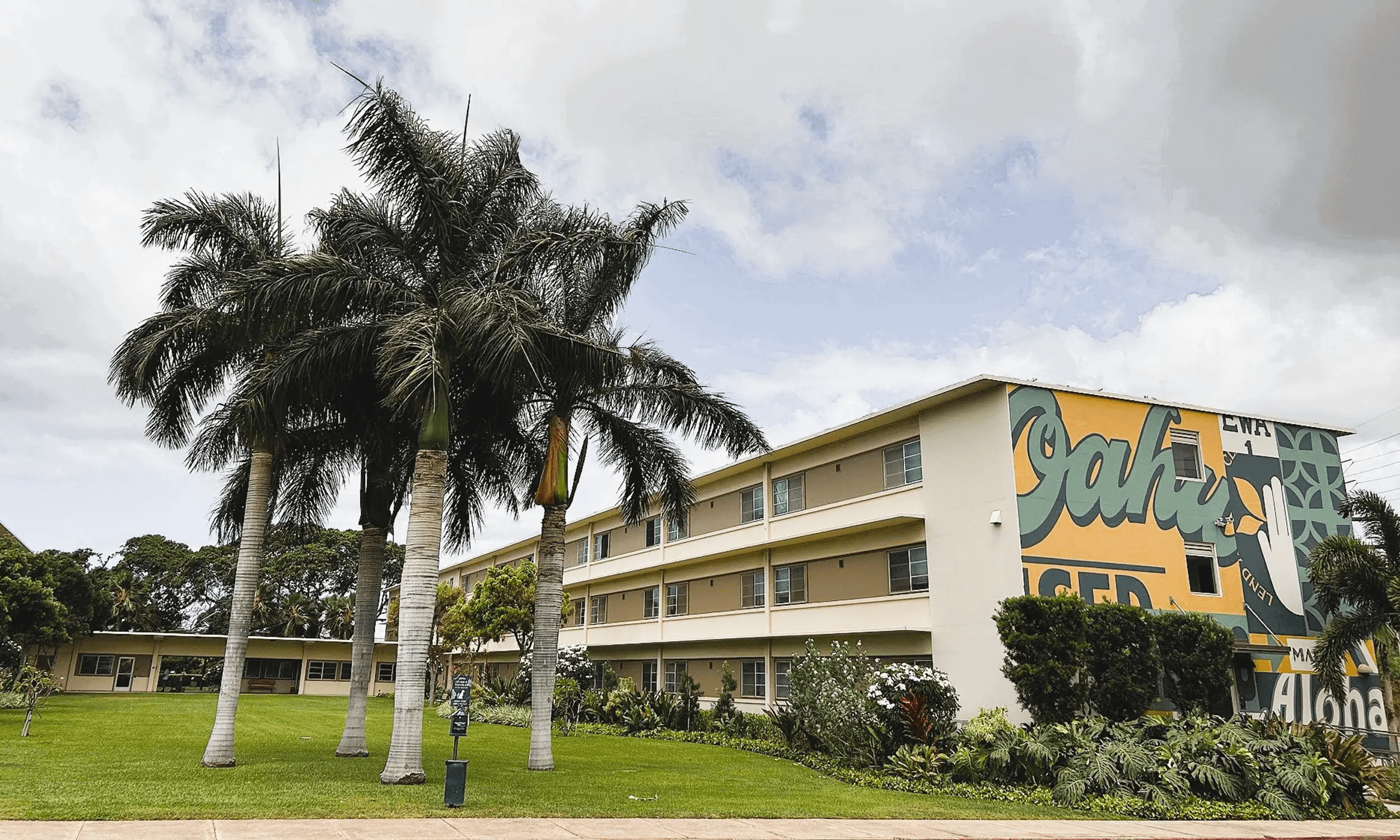 Exterior of 3-story building with a mural painted on one of it's sides.