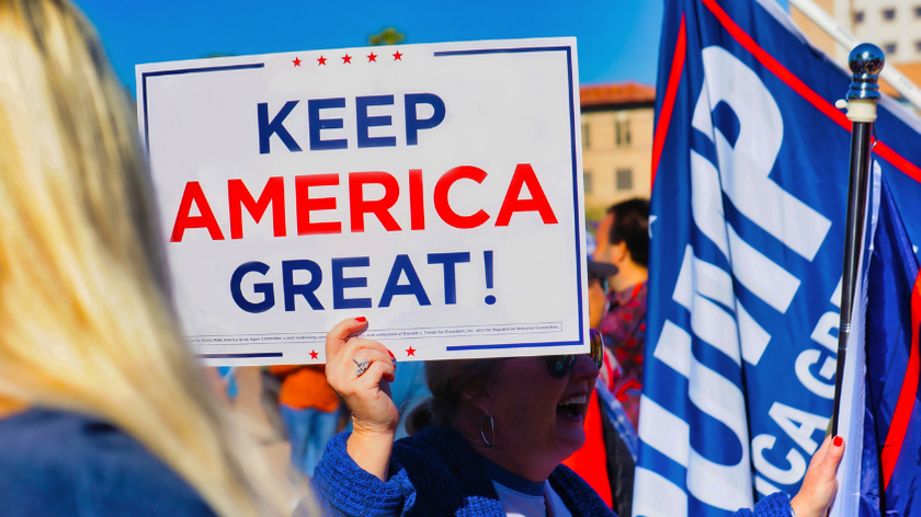 A woman holds a sign that reads "Keep America Great!"