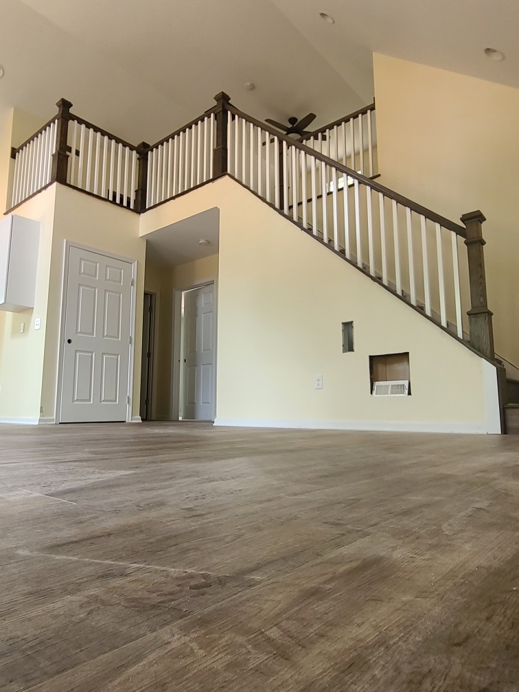 Expansive traditional staircase with white spindles and richly stained handrails complementing the wide, inviting entryway.