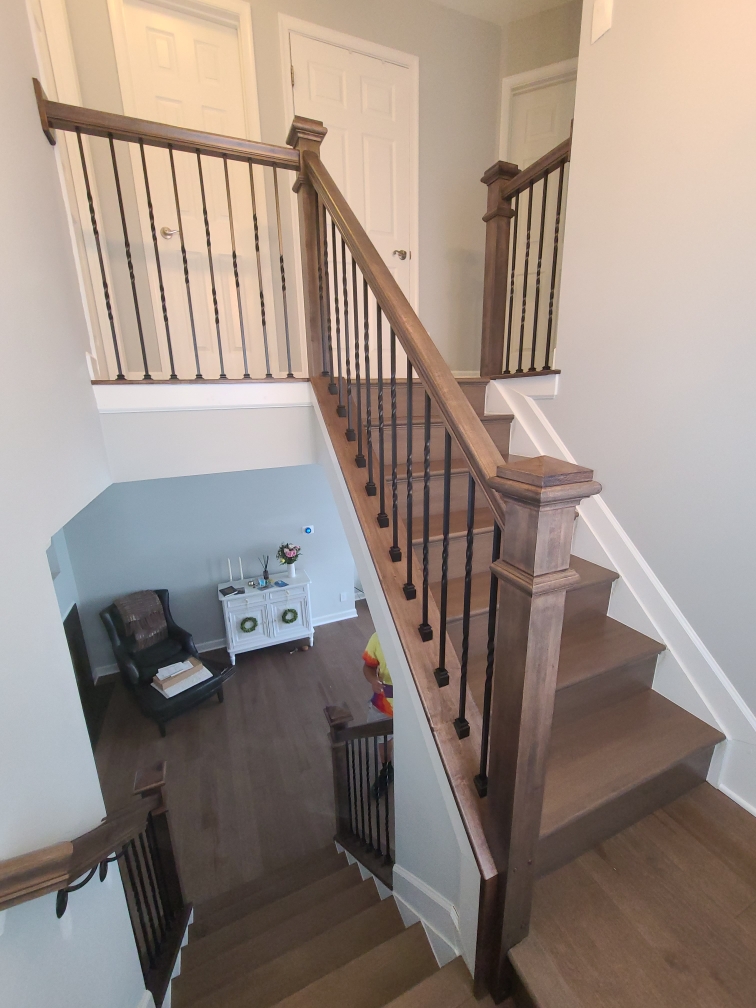 Overlooking view of a wooden staircase with a rich finish, featuring turned balusters and newel posts, enhancing the home's warm ambiance.