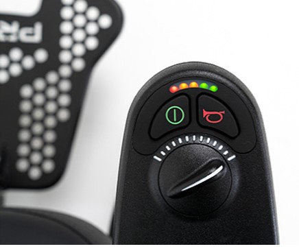 Close up view of wheelchair controller with speed dial turned up all the way. Led battery indicator is visible as well