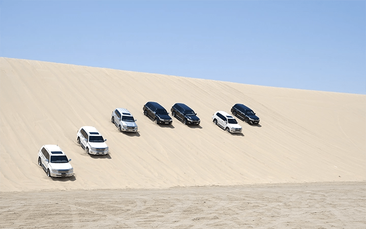 SUVs driving over desert dunes in Wild Dunes Desert Safari Qatar