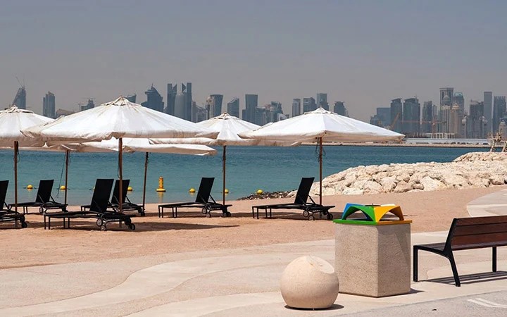 Scenic Doha skyline seen from 974 Beach Qatar with umbrellas on the sand