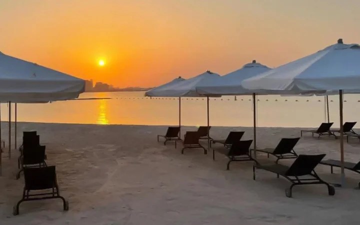 Golden sunset over 974 Beach Qatar with calm waters and loungers