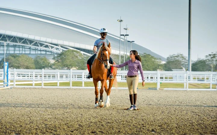 Rider with trainer guiding Arabian horse at Al Shaqab Equestrian Complex in Doha Qatar