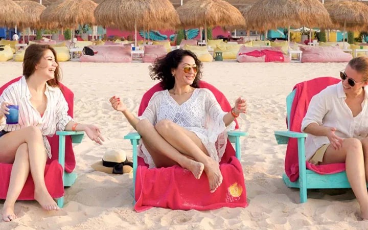 Women enjoying cabana chairs on the sandy beach at Doha Beach Club Qatar