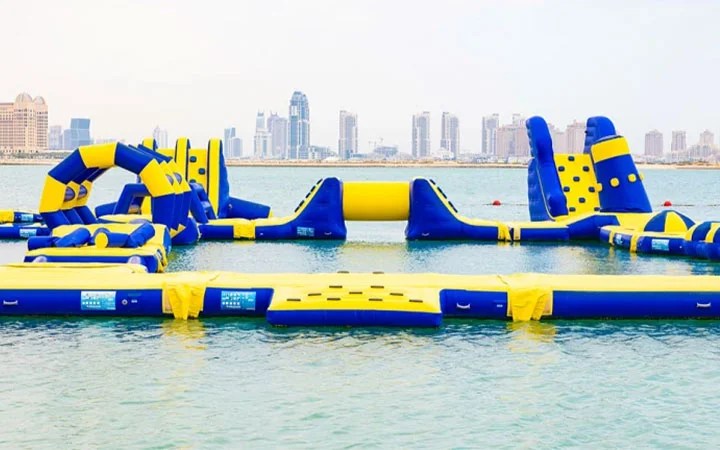 Inflatable water park activities at Doha Beach Club with Doha skyline view
