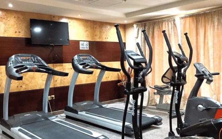 A gym room at this Tourist Hotel offers two treadmills, two elliptical machines, and a stationary bike. Enjoy workouts during your 3-star stay while watching the wall-mounted TV; large curtains cover the windows in the background.