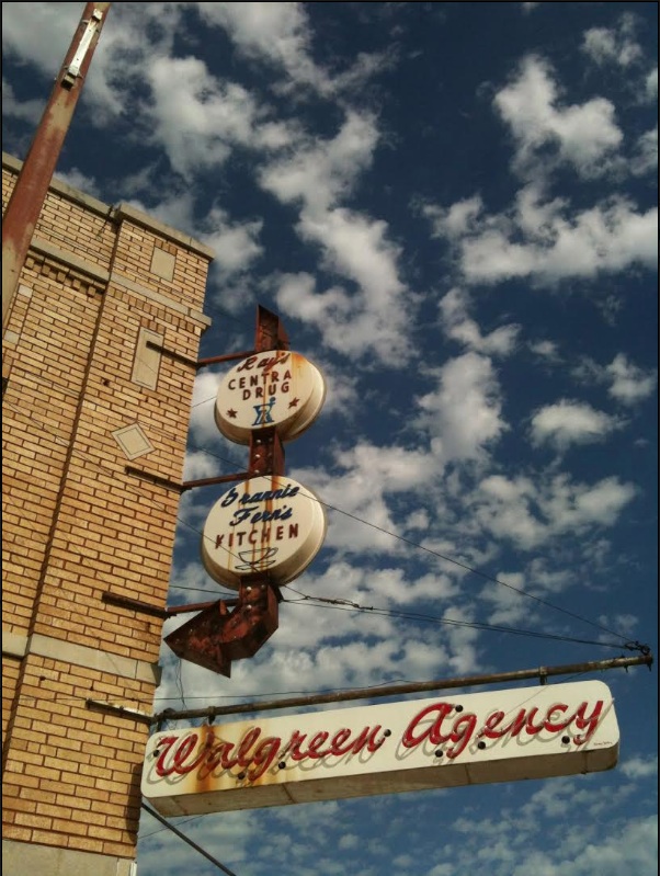 Old Walgreens sign in downtown Seminole, OK. Blue sky with white clouds in background.