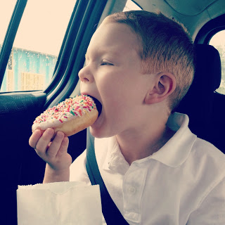 Pre-K child taking a bite of donut.