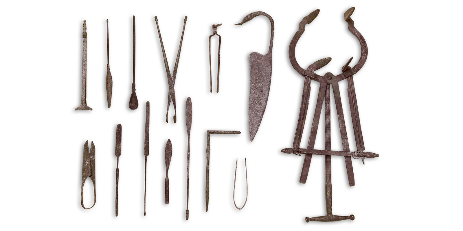 Array of reddish-brown stick-like tools and knives in two rows. To the right is a large horseshoe-shaped tool with thin, flat strips of metal. 