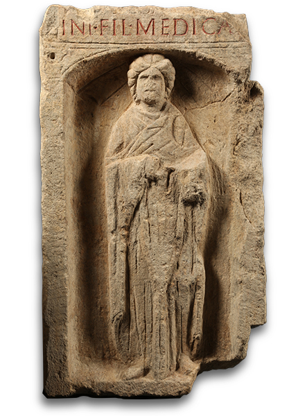 Brownish stone niche containing a high-relief sculpture of a robed female figure. A line of text is inscribed above the niche and painted red. 