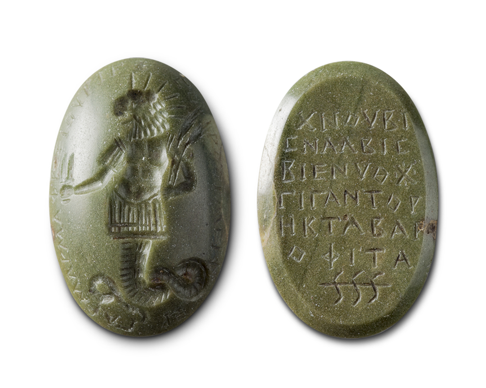 The front and back of a greenish-brown stone. On the left, the front view shows a lion-headed creature; on the right, the flat beveled back has been inscribed with lines of text.