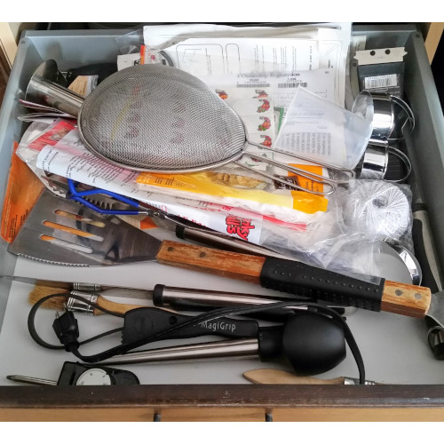 A messy kitchen drawer before it was decluttered. Using these 6 decluttering tips will help you clear out the clutter.