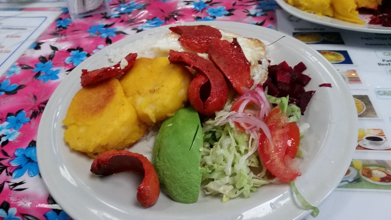 Plate with llapingacho dish of potatoes, sausage, avocado, lettuce, rice, egg and beats.