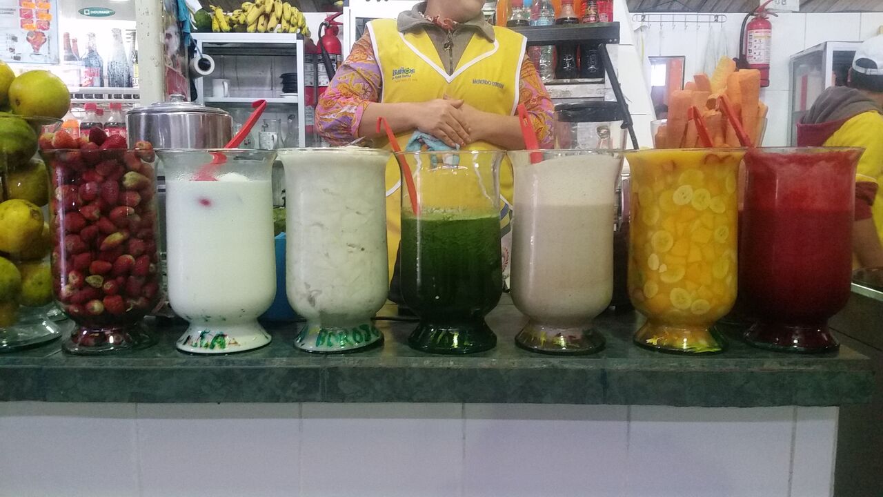 7 glass jars with fresh juice in them including red, white, green and yellow fruits.