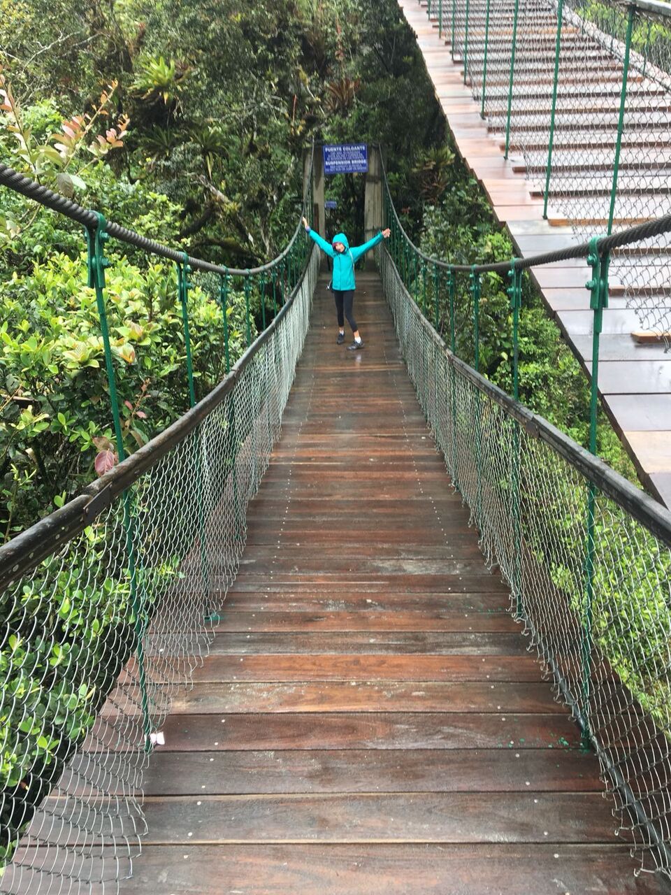 Girl on wooden bridge at Pailon del Diablo waterfall.