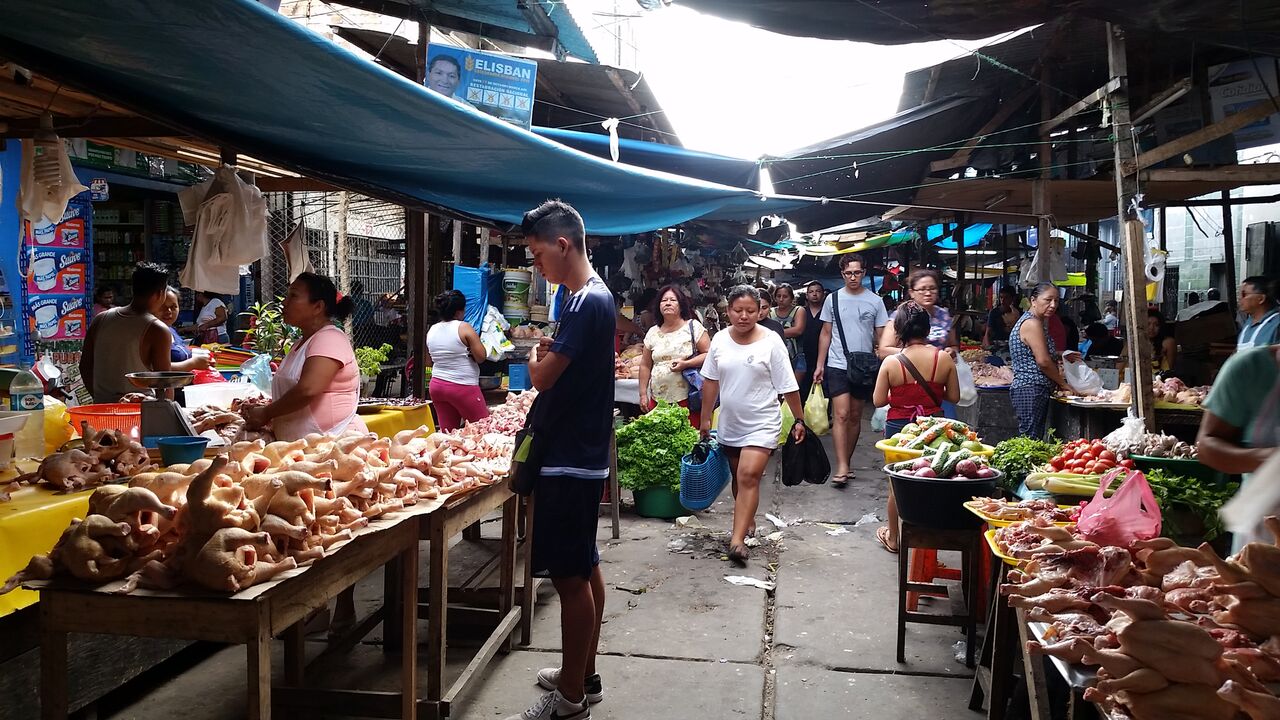 Boy in black shirt looking at meat in Belen market Iquitos