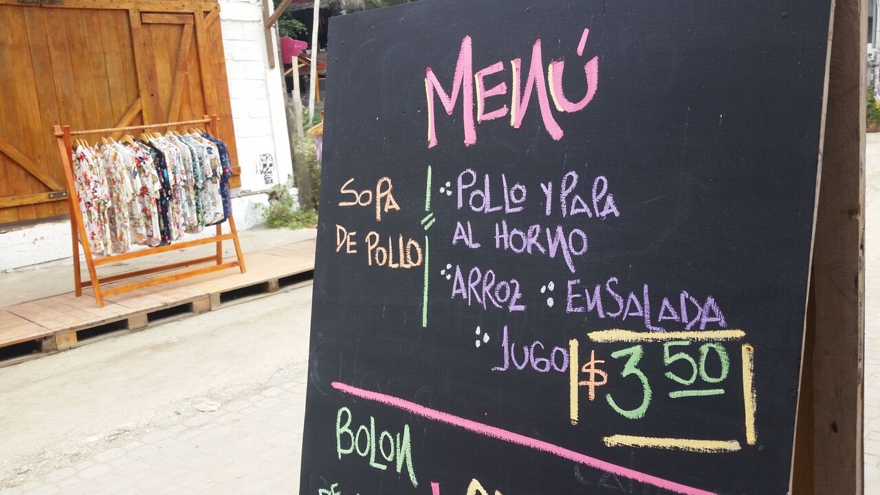 Chalkboard with pink and purple writing "menu" and hawaiian shirts in the background.