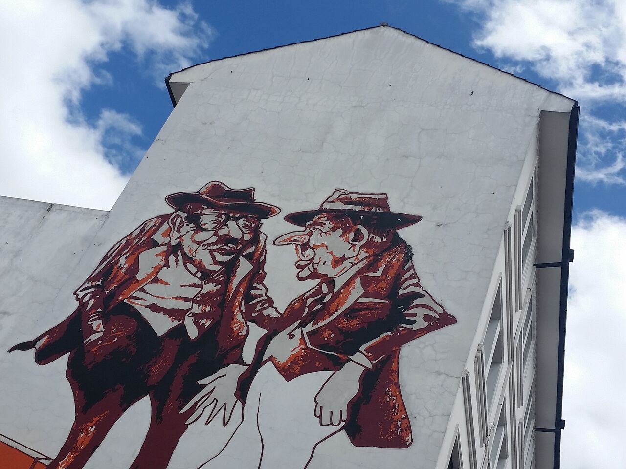 White building with brown and red painting of old men.