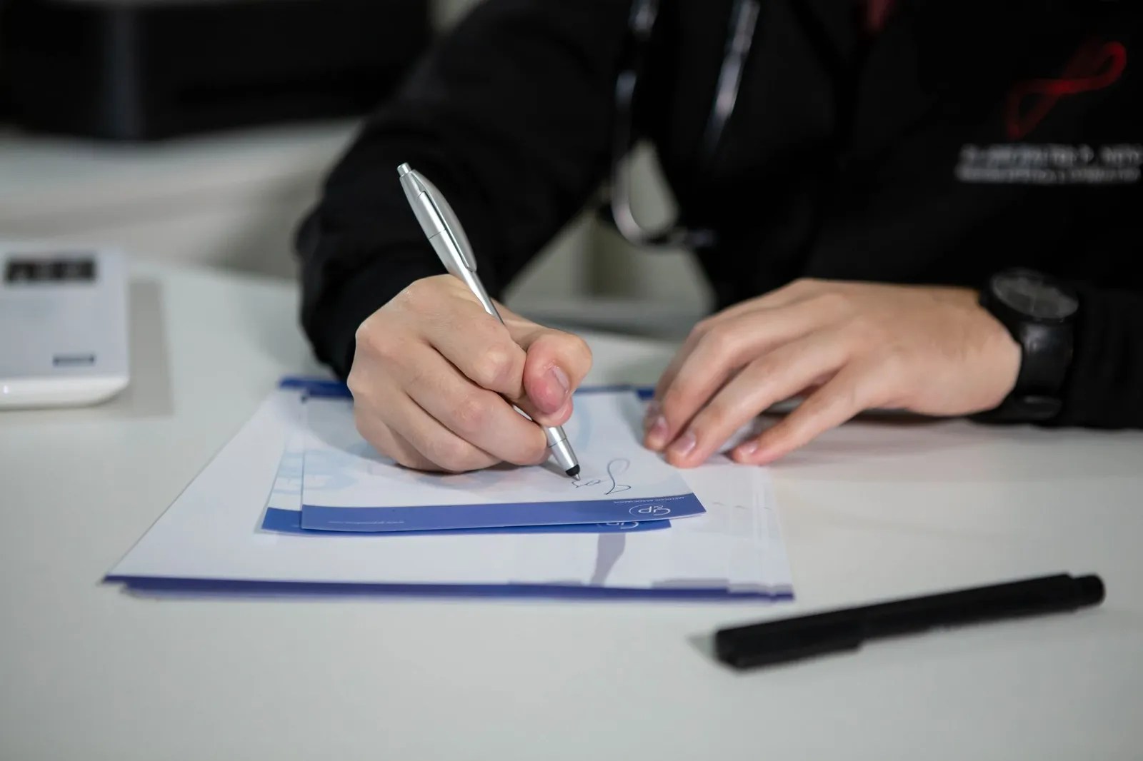 Medical professional writing clinical notes at a desk