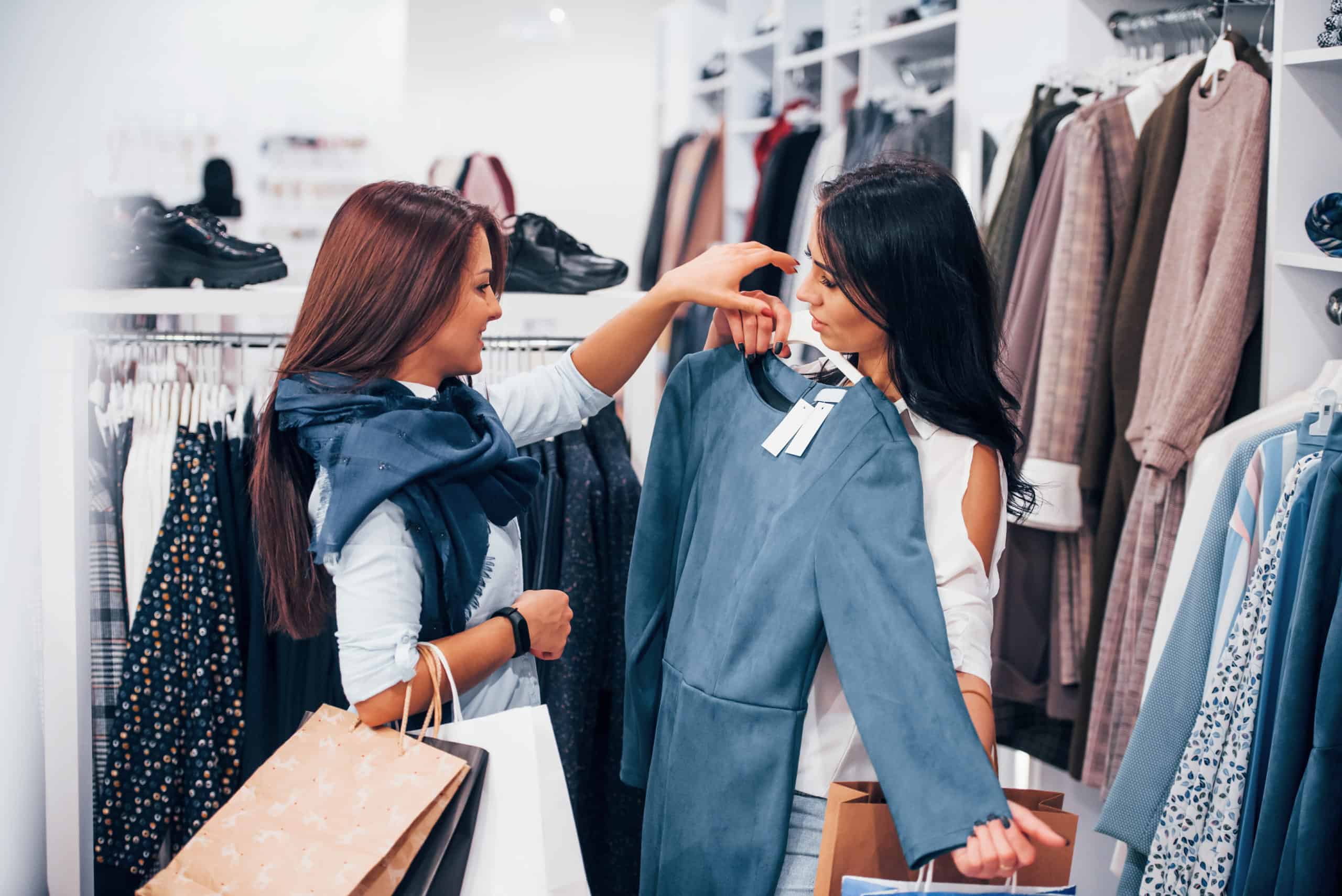 dos personas en un almacen de ropa probandosen como les queda la ropa en venta