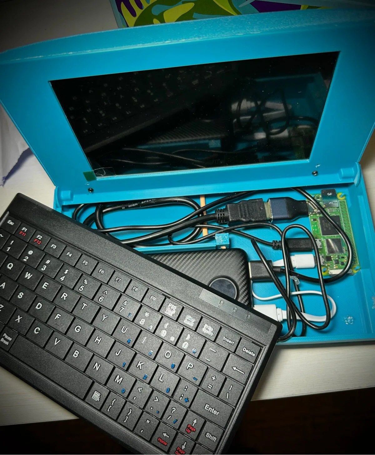 Open turquoise laptop case with exposed keyboard and internal circuit board and wires.