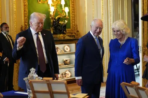 Aaron Chown/WPA Pool/Getty Images US President Donald Trump (L) and King Charles III view items on display during a visit to the Royal Collection exhibition, in the Green Drawing Room during the State visit by the President of the United States of America at Windsor Castle on September 17, 2025 in Windsor, England.