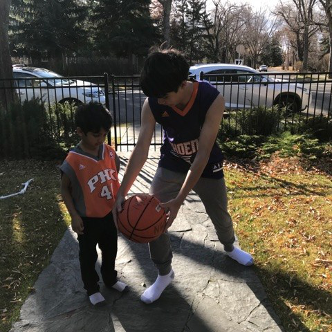 Benjamin teaching Neil how to play basketball.